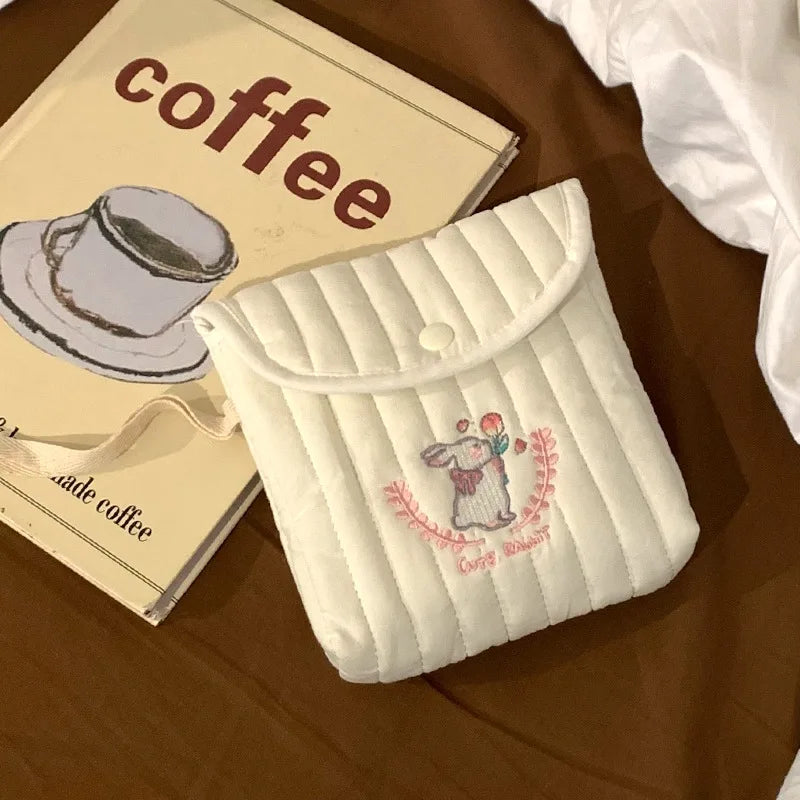 Small quilted pouch with a cute design on a wooden surface next to a coffee-themed book.