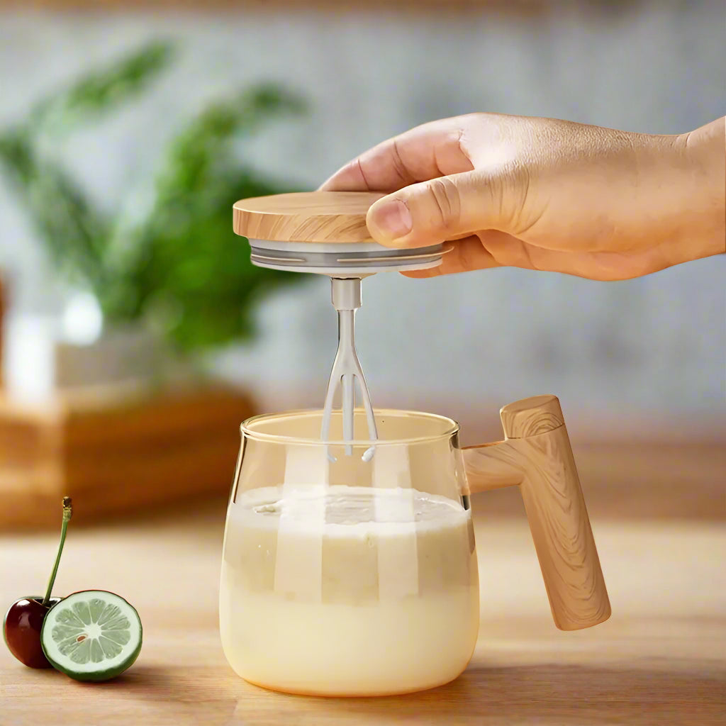 Hand using a milkshake mixer to stir a glass of milkshake.