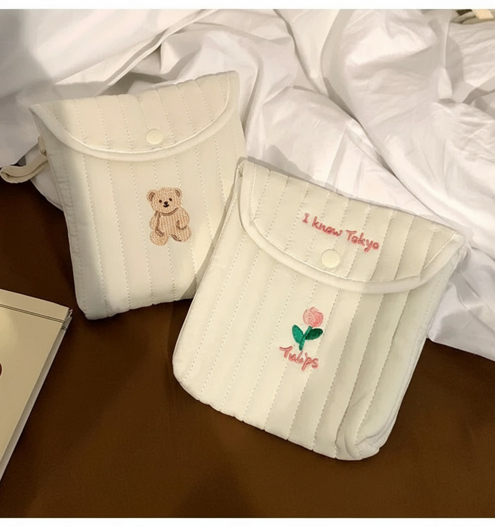 Two small pouches with embroidered designs on a wooden surface.