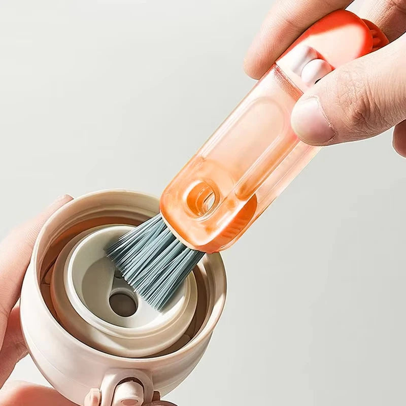 Person using a small brush to clean inside a ceramic container with an orange handle.