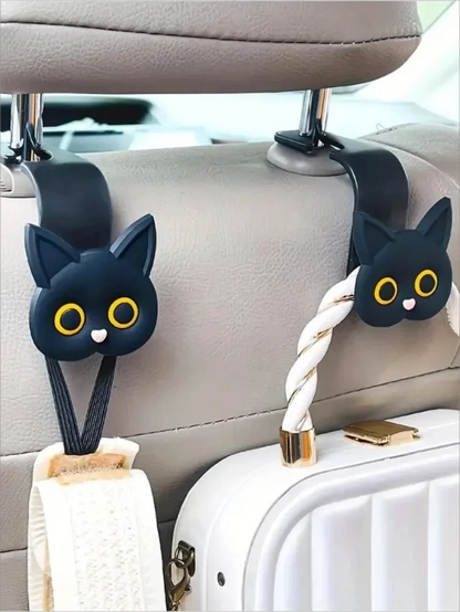 Two black cat-shaped car hooks attached to a car's headrest.